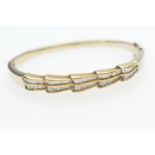 Diamond bangle, set with small baguette cut diamonds, channel set in two graduating rows, on an