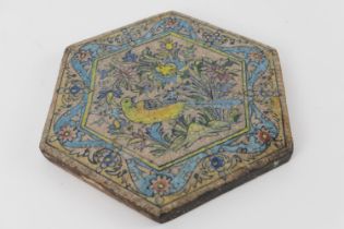 Qajar decorated hexagonal tile, centred with a bird amidst foliage within a blue wavy floral border,