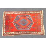 Pakistani red ground woollen rug, centred with a blue medallion within a fawn border, 160cm x 96cm