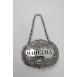 William IV silver decanter label, pressed with grapes and a satyr, pierced 'Madeira', on a silver