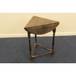 Victorian carved oak cricket table, with a swivelling drop leaf circular top, carved with leaves,