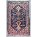 An Early 20th Century Shiraz Rug woven in colours of ivory, navy blue and wine, with five hooked