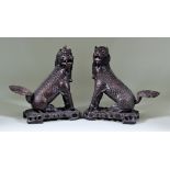 A Pair of Chinese Hardwood Seated Kylin, 20th Century, with glass eyes and on pierced bases,