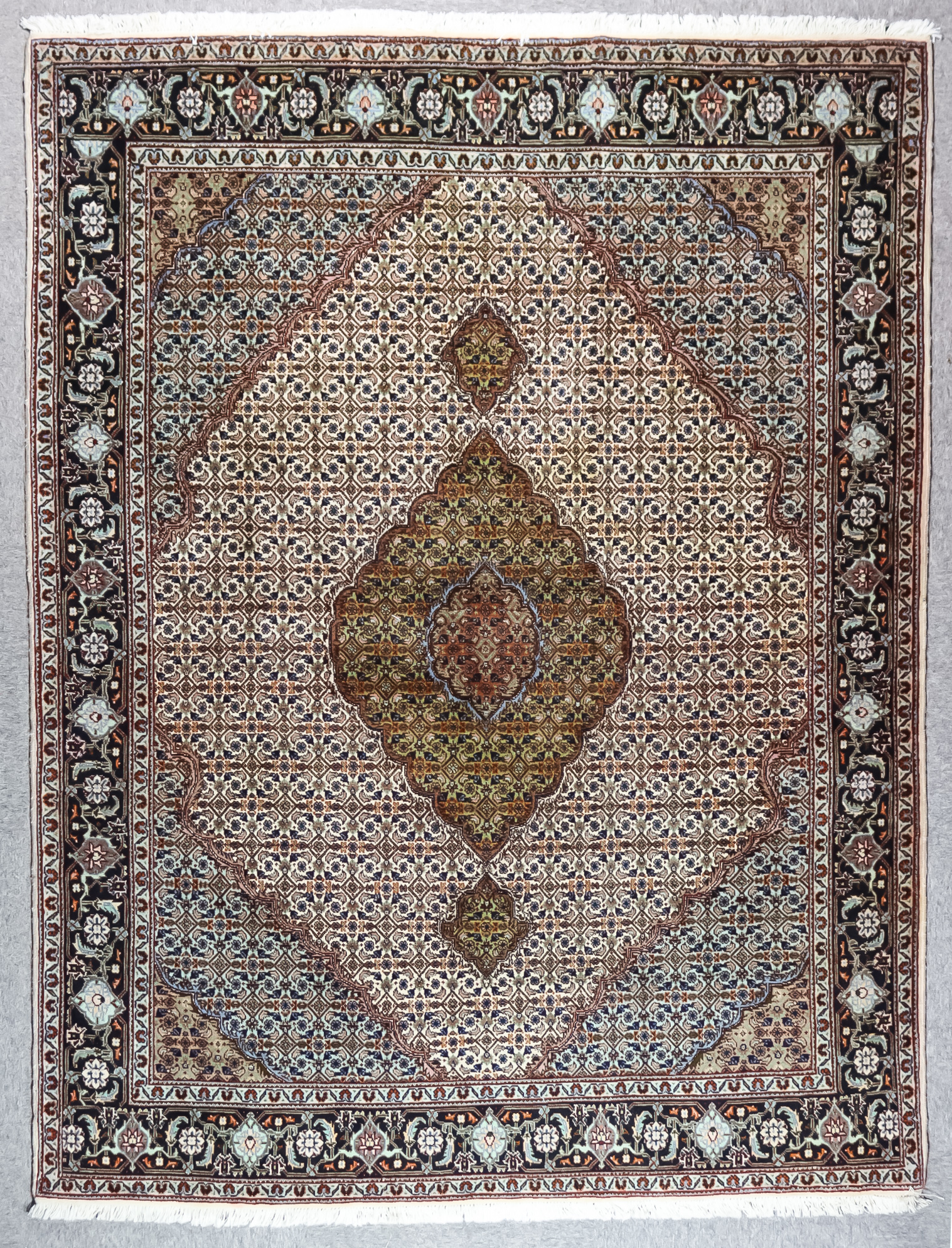 An Early 20th Century Fine Part Silk Tabriz Rug woven in colours of ivory, pastel blue and green,