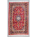 A Mid 20th Century Kashan Rug woven in colours of wine, ivory and navy blue with a central floral