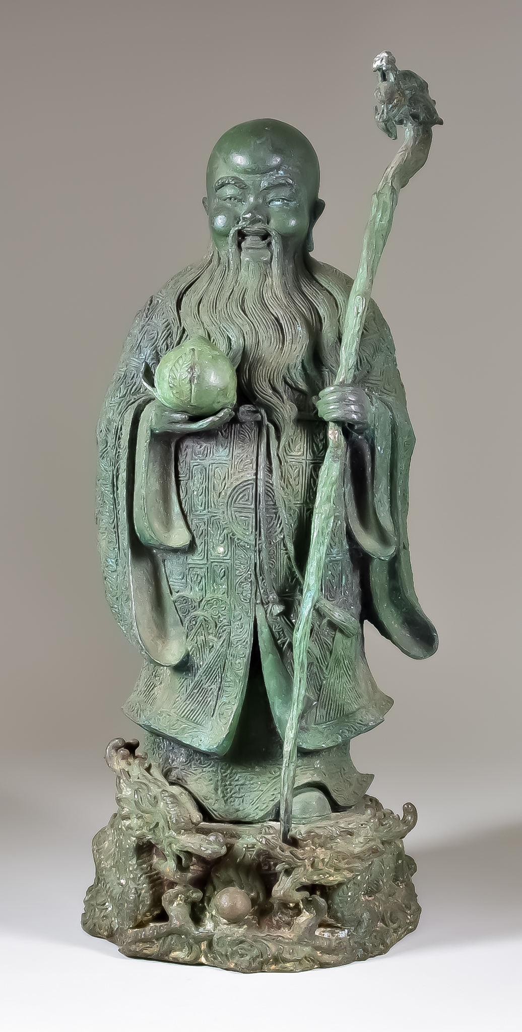 A Chinese Bronze Figure of Shou-Lao, Daoist God of Longevity, holding a dragon staff and peach, 19.