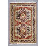 A Mid 20th Century Rug of Kazak Design, woven in colours of navy blue, ivory and wine, with two bold