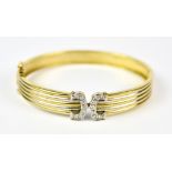 An 18ct Gold Diamond Set Stiff Bangle, set with sixteen small diamonds to a centre motif, 55mm