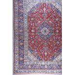 An Early to Mid 20th Century Kashan Carpet, woven in colours of ivory, navy blue and wine, the