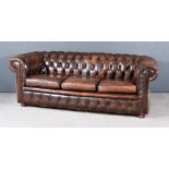 A Chesterfield Three Seat Settee, upholstered in brown leather, the back buttoned, on bun feet,