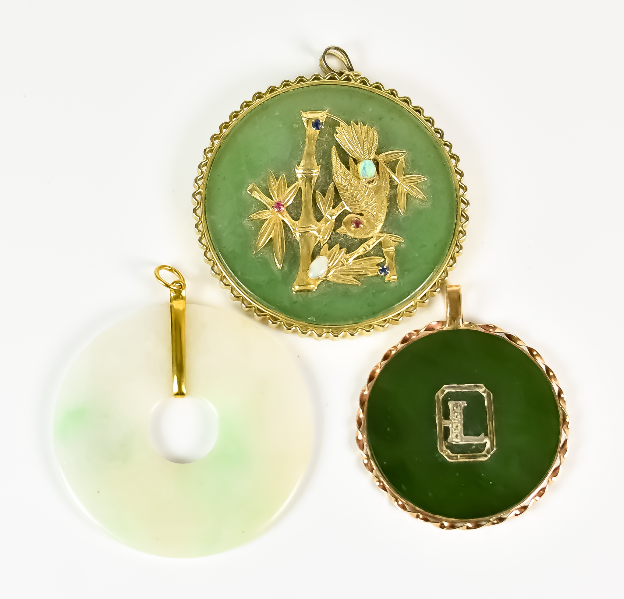 Three Oriental Jade Pendants, 20th Century, one depicting a bird in bamboo set with small gems, 55mm