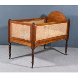 A 19th Century Mahogany and Cane Panelled Cot, with arched headboard, on turned legs and castors,