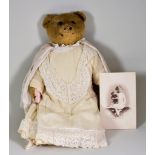 An English Teddy Bear, Early 20th Century, with golden mohair and black button eyes, with lace