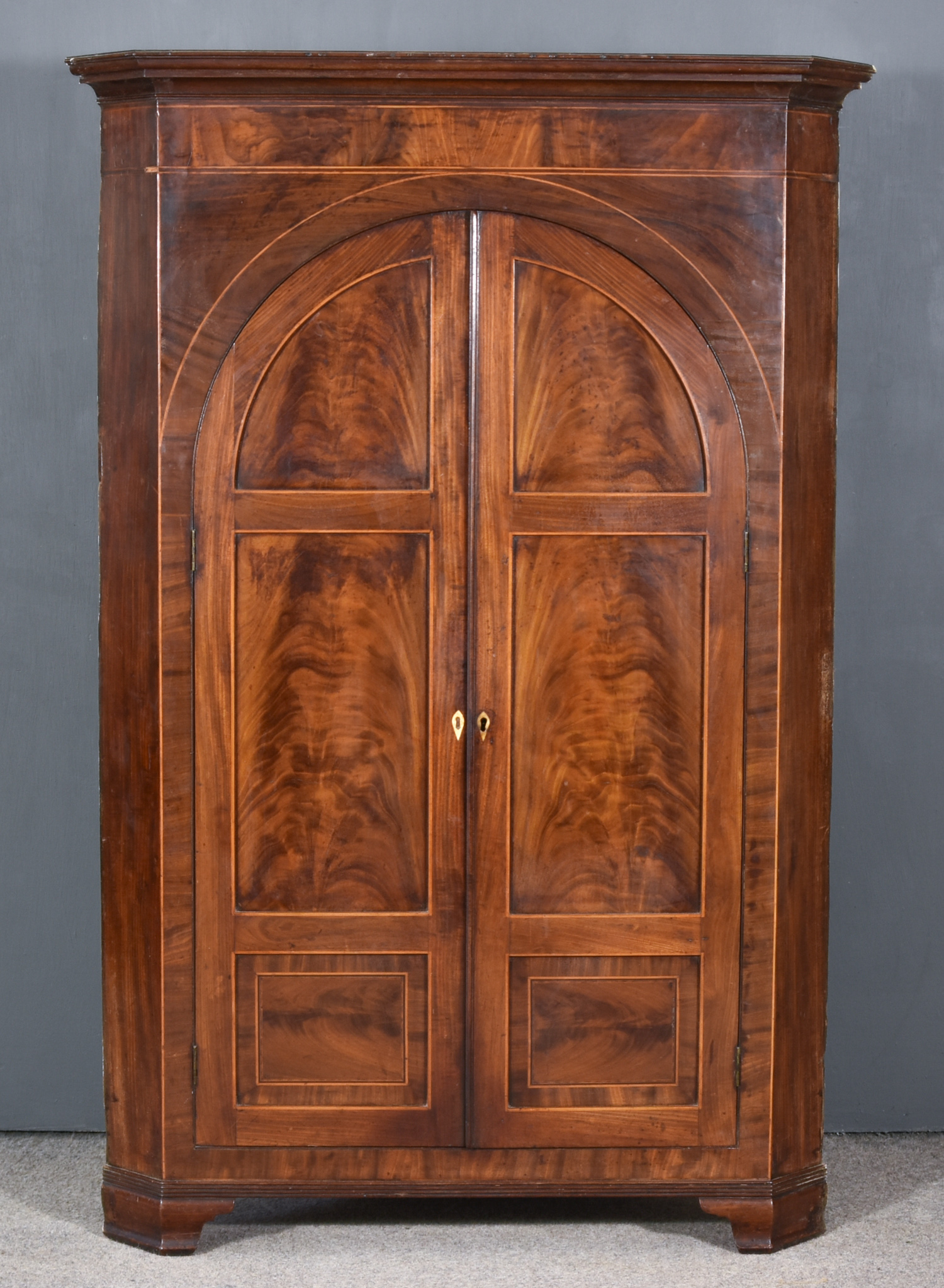 A George III Figured Mahogany Hanging Corner Cupboard, fitted three shelves and two small drawers,