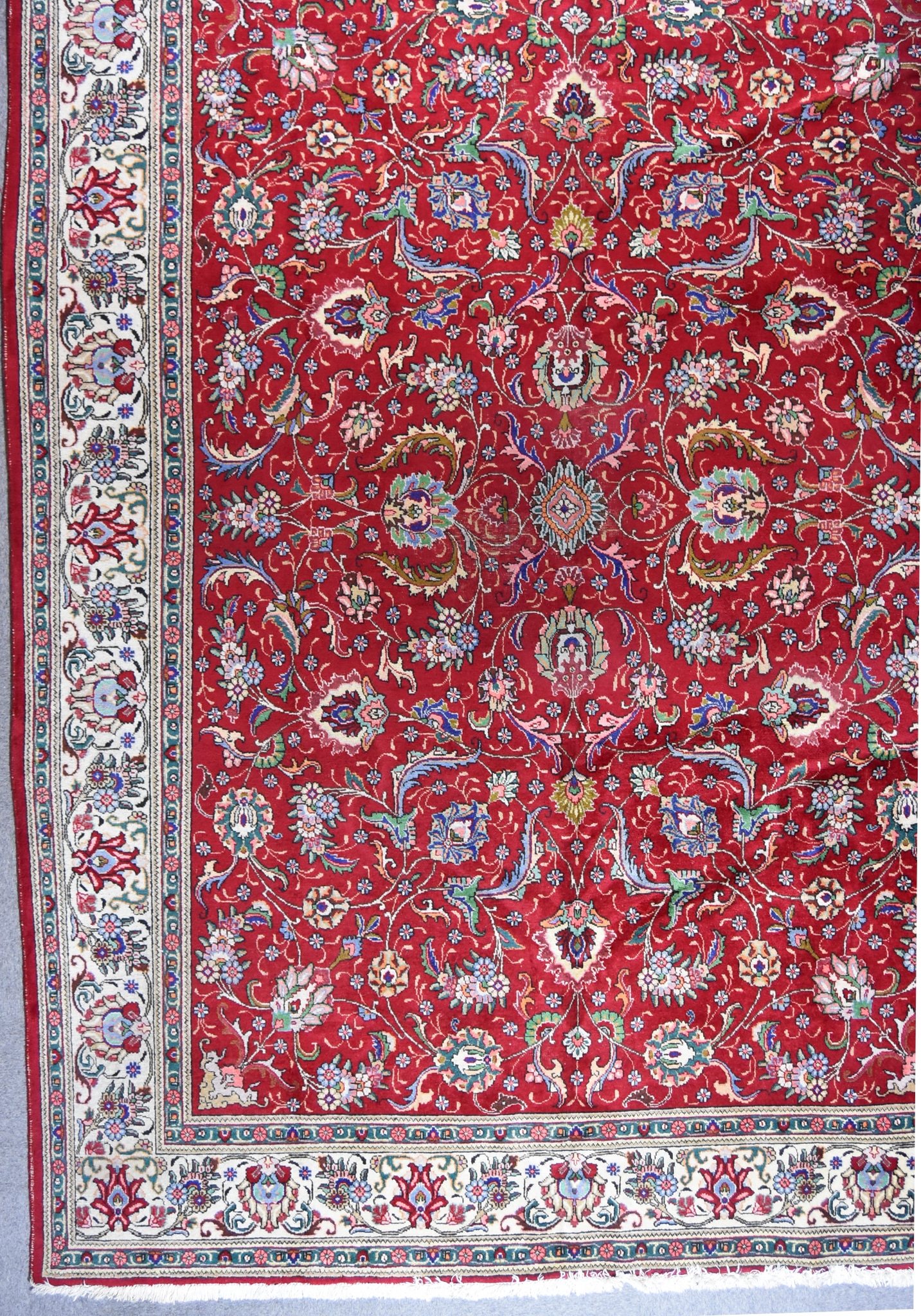 An Early 20th Century Tabriz Carpet, woven in colours of ivory, navy blue and wine, the field filled