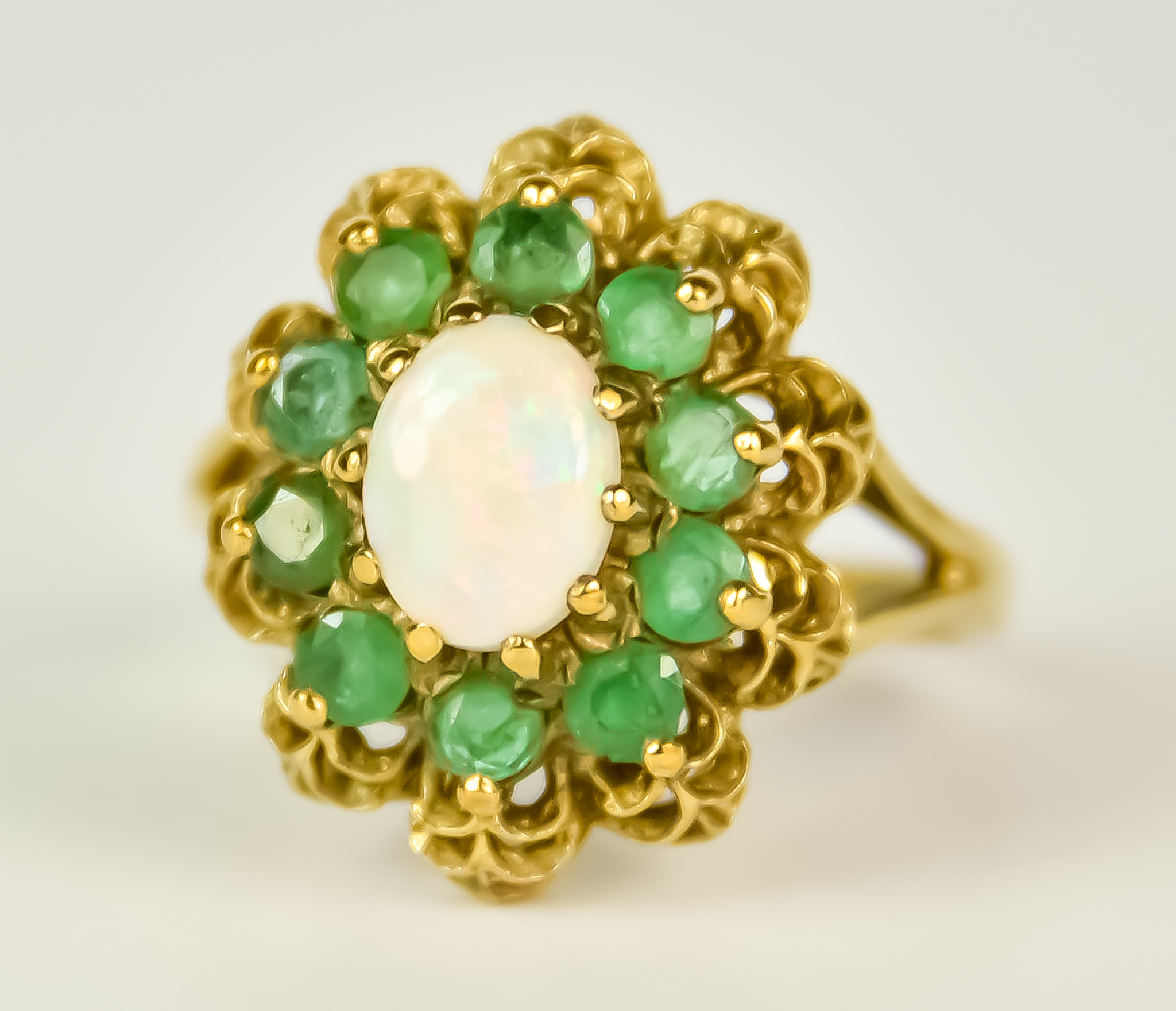 A 9ct Gold Emerald and Opal Ring, 20th Century, set with a centre opal, 6mm x 7mm, surrounded by ten