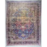 A 19th Century Kirman Carpet, woven in colours of navy blue, ivory and wine, with a bold central