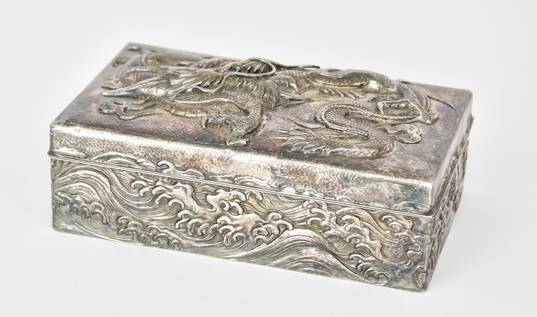 A Chinese Silvery Metal and Hardwood Rectangular Cigarette Box, the lid embossed with dragon, the