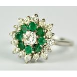 An 18ct White Gold Diamond and Emerald Flower Head Ring, 20th Century, set with a centre brilliant