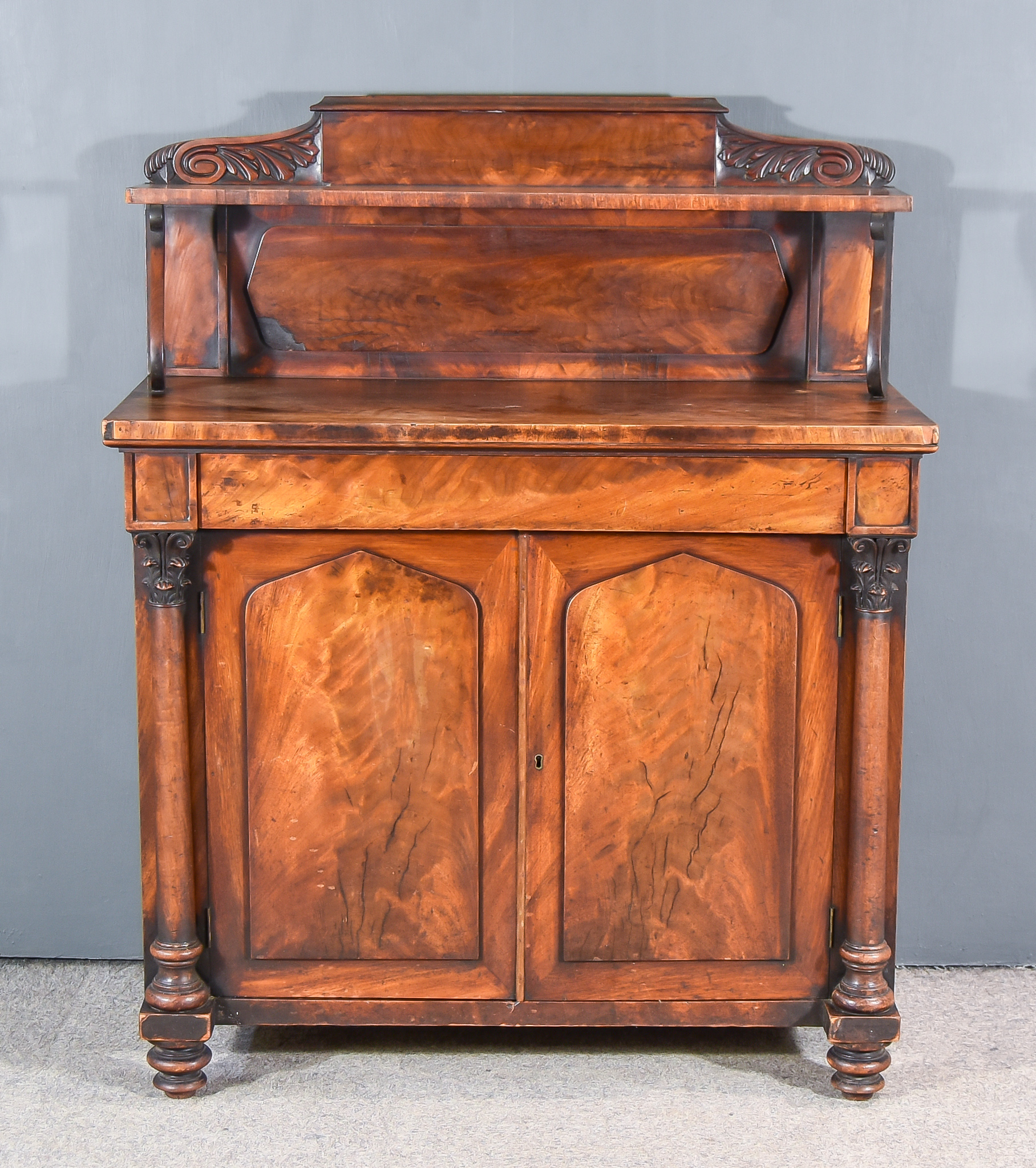 An Early Victorian Mahogany Chiffonier, the upper part with leaf carved cresting above shelf, on