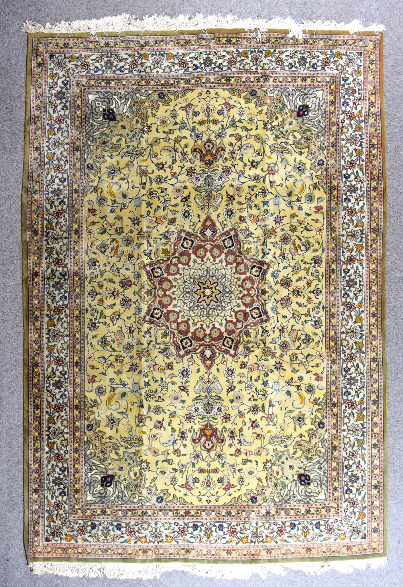 A 20th Century Tabriz Carpet, woven in colours of lime, mint and wine, with a bold central floral