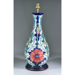 A Moorcroft Pottery Table Lamp on Wooden Base decorated in Thistle Poppy pattern on a navy blue