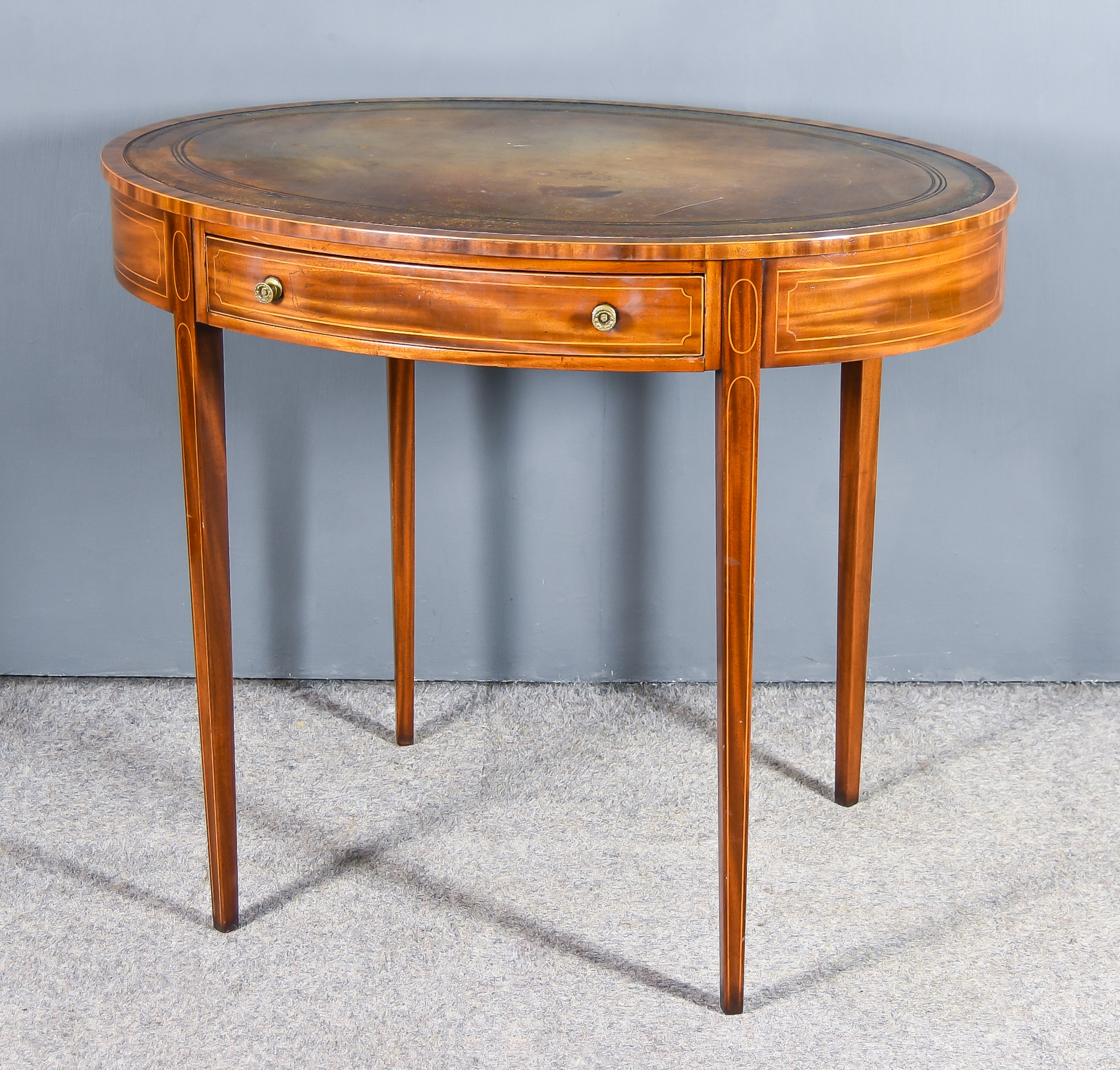 An Edwardian Oval Writing Table of Georgian Design, inlaid with stringings, with leather inset to