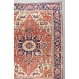 An Early 20th Century Heriz Carpet, woven in colours of ivory, navy blue and wine, with a bold