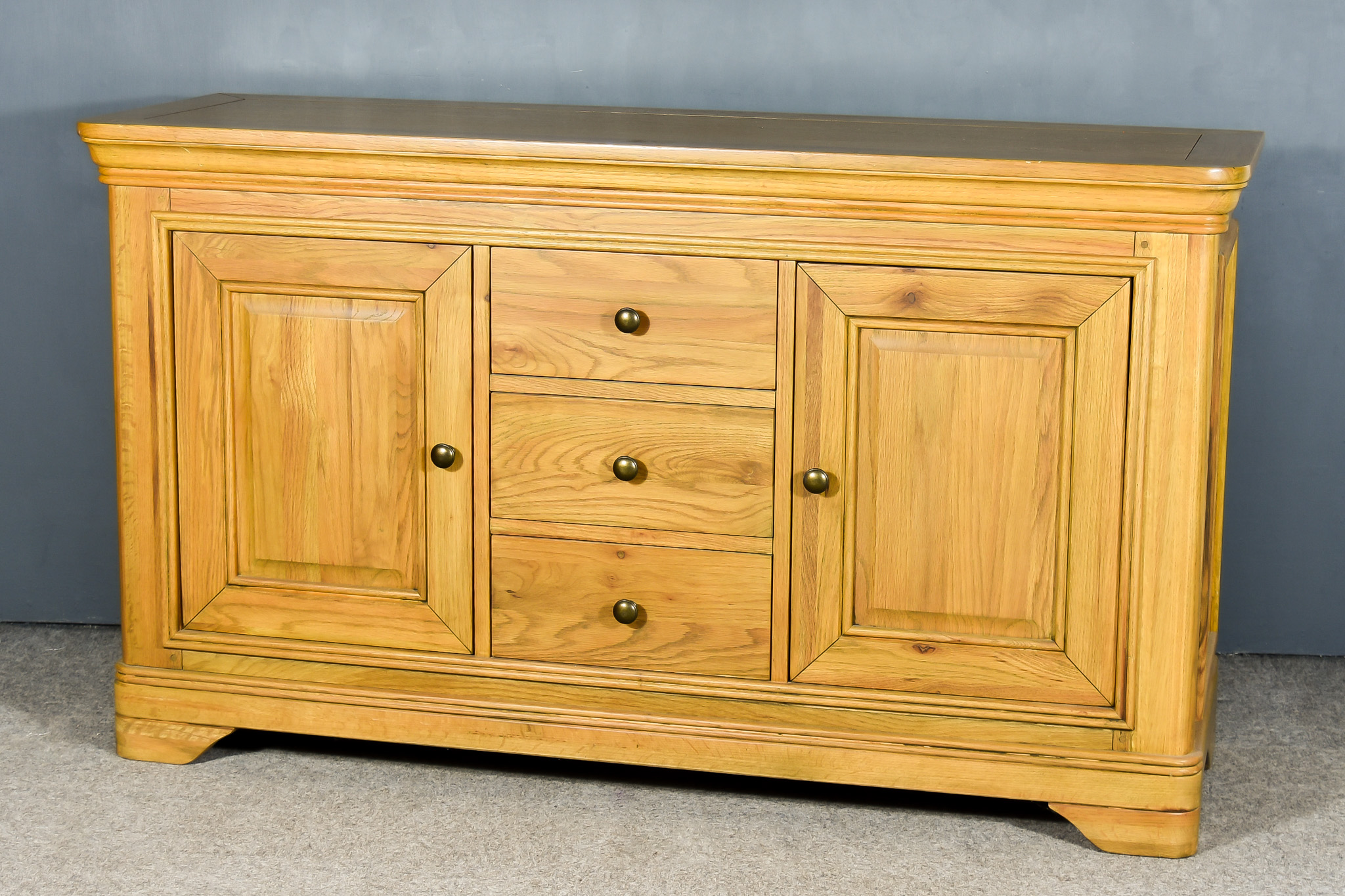 A Modern Oak Sideboard in the French Provincial Manner, with flush panelled top and rounded front