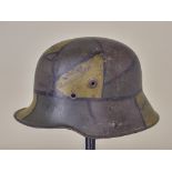 A World War I German Steel Helmet, marked KG, painted in Glimmer Camoflague with partial liner