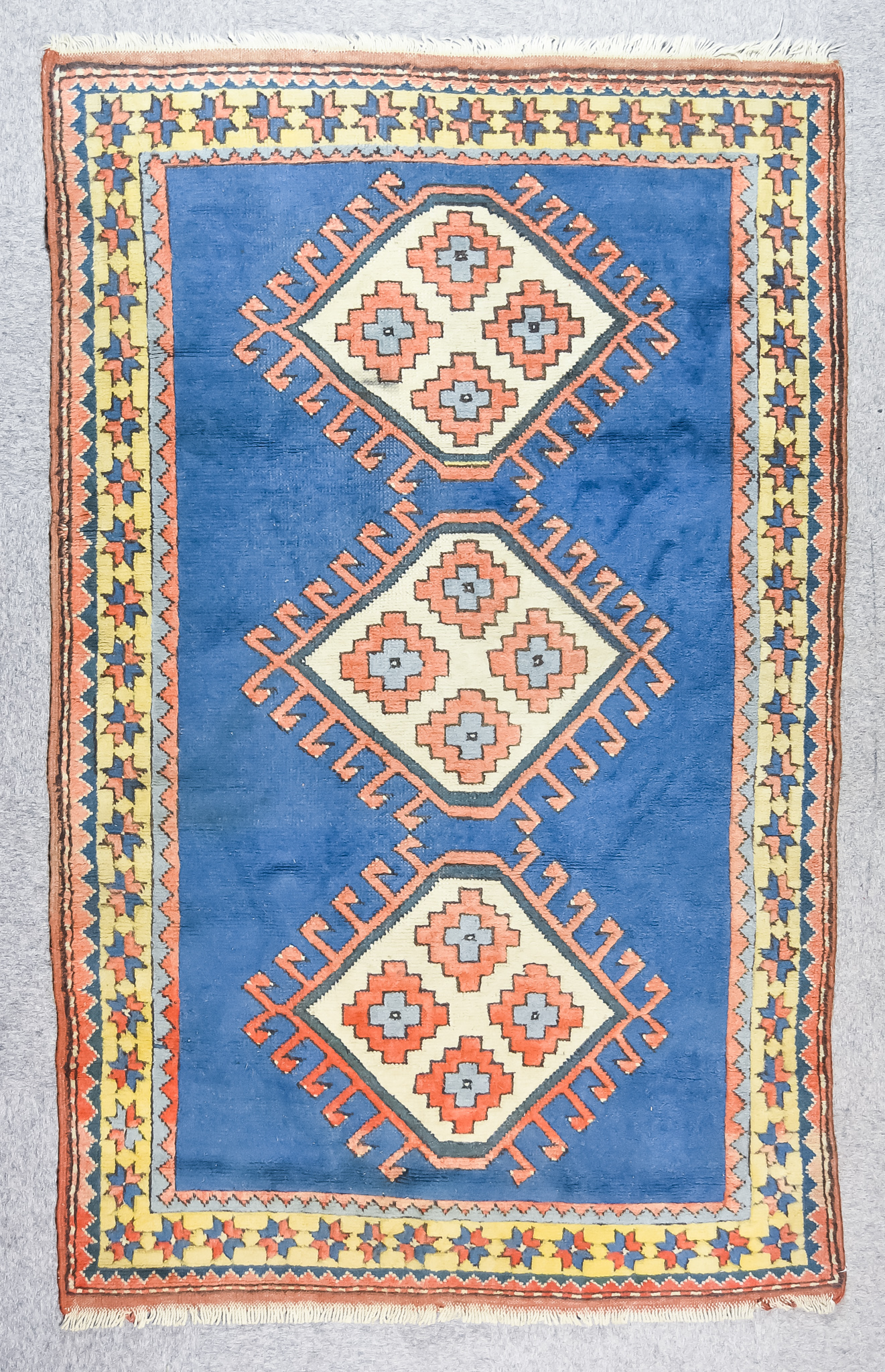 An Anatolian Rug of "Kazak" Design, woven in colours of terracotta, navy blue and fawn, with three