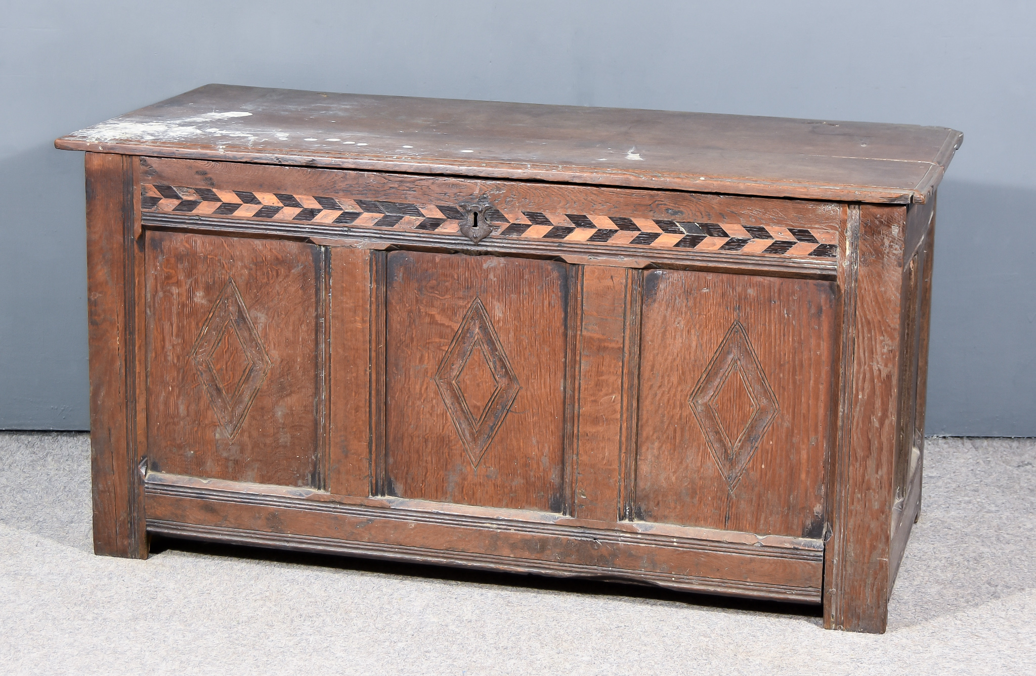 An Old Panelled Oak Coffer, the two plank top with moulded edge, frieze inlaid with chequered