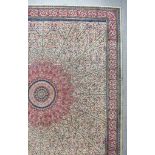 An Antique Tabriz Carpet, woven in colours of ivory, navy blue and wine, with a bold stylised floral