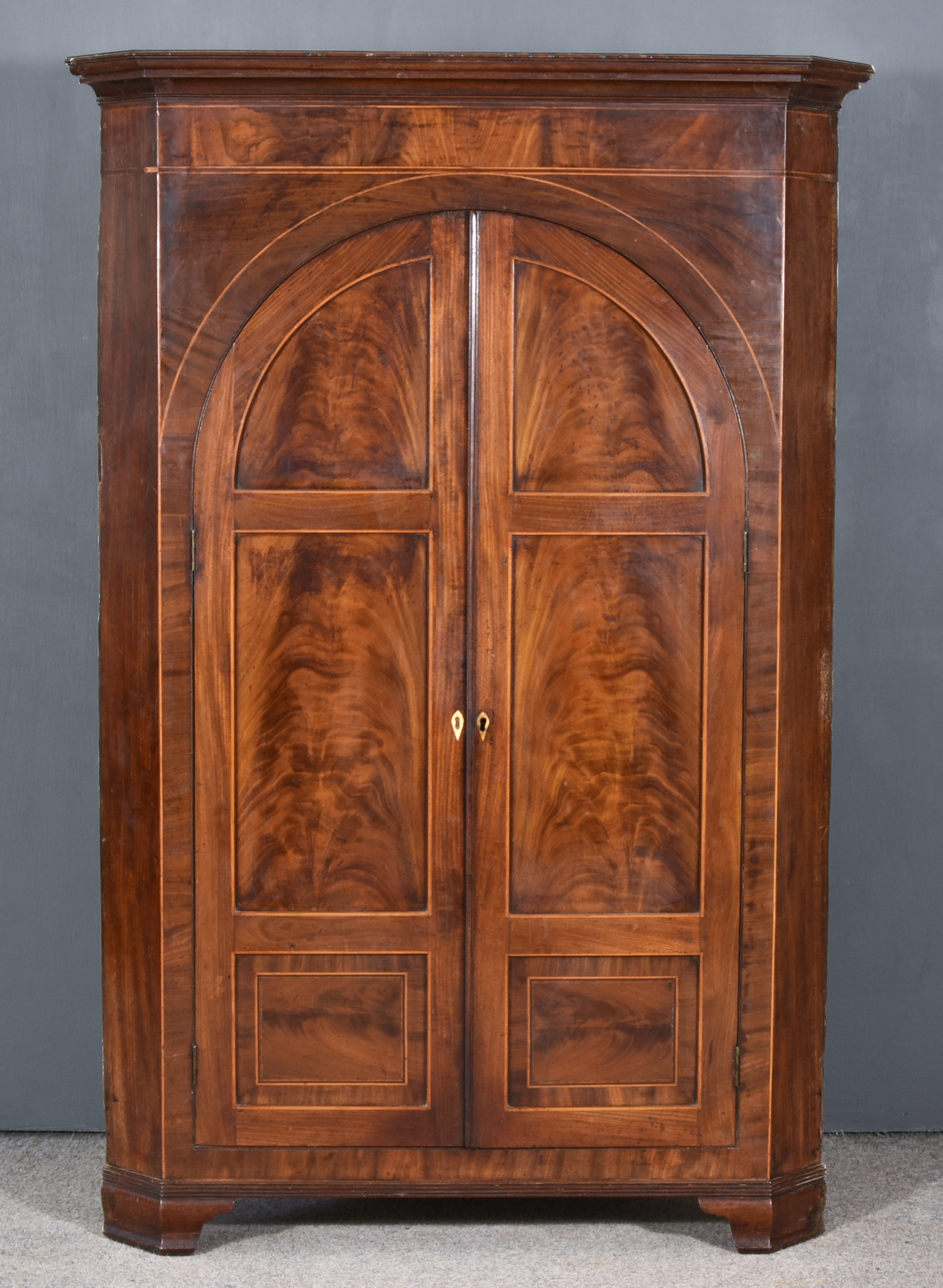 A George III Figured Mahogany Corner Cupboard, fitted three shelves and two small drawers,