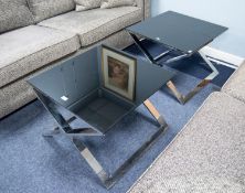 PAIR OF SQUARE LAMP TABLES, with black glass tops, on polished steel base with 'X' framed supports