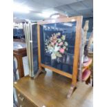 AN ELM CHEVAL GRATE SCREEN WITH GLAZED AND FLORAL NEEDLEWORK TAPESTRY PANEL AND A BRASS FRAMED AND