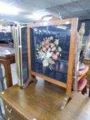 AN ELM CHEVAL GRATE SCREEN WITH GLAZED AND FLORAL NEEDLEWORK TAPESTRY PANEL AND A BRASS FRAMED AND