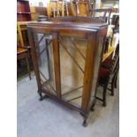 AN OAK DISPLAY CABINET, ENCLOSED BY TWO DOORS AND RAISED ON CABRIOLE SUPPORTS