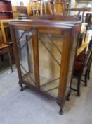 AN OAK DISPLAY CABINET, ENCLOSED BY TWO DOORS AND RAISED ON CABRIOLE SUPPORTS