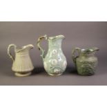 RIDGWAY OR AFTER, THREE RELIEF MOULDED AND PALE GREEN GLAZED POTTERY JUGS, one modelled in the ?