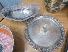 AN ELECTROPLATE PIERCED OVAL PEDESTAL CAKE DISH AND A SILVER ON COPPER CHASED CIRCULAR SALVER WITH