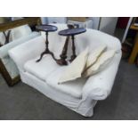 A TWO SEATER SETTEE, COVERED IN WHITE LINING AND THE PLAIN WHITE COTTON LOOSE COVERS