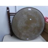 MIDDLE EASTERN ENGRAVED BRASS COFFEE TABLE WITH CIRCULAR TOP AND FOLDING WOOD BASE, lacking one