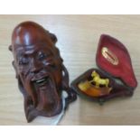 A SMALL ORIENTAL CARVED WOOD MASK HEAD WALL ORNAMENT AND A SMALL MEERSCHAUM PIPE BOWL SURMOUNTED