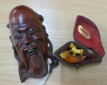 A SMALL ORIENTAL CARVED WOOD MASK HEAD WALL ORNAMENT AND A SMALL MEERSCHAUM PIPE BOWL SURMOUNTED