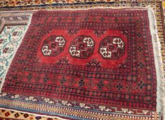 TURKOMAN BOKHARA RUG decorated with three large primary guls on a wine red field, the principal