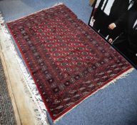 PAKISTAN BOKHARA RUG with three rows of small guls in black and white on a dark wine red field,