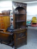 A 'J.C.' OAK FLOOR STANDING CORNER CABINET, THE UPPER SECTION HAVING OPEN SHELVES OVER A CARVED