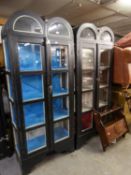 PAIR OF BLACK PAINTED TWO DOOR DISPLAY CABINETS, each with twin arched and glazed tops, shaped base,