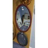 TWO PAINTED OVAL WALL MIRRORS, one in red with bevel edged plate, 29? x 19 ½?, the other grey, 23? x